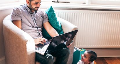 Man studying on a laptop while looking after a baby