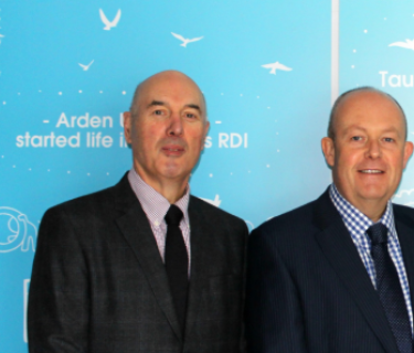 Arden University's Vice-Chancellor and International Director stand in front of an Arden University poster