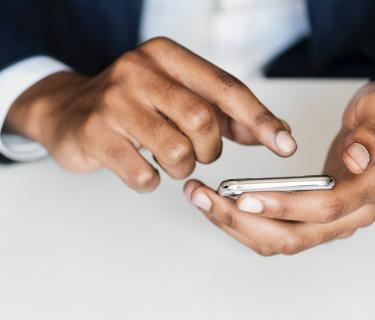 A pair of hands typing on a smart phone