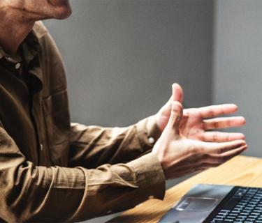 Man holding his hands out over a laptop