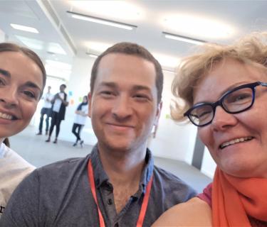 Two women and a man taking a selfie together