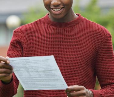 Student standing and holding a piece of paper