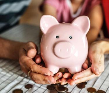 Family holding piggy bank on table