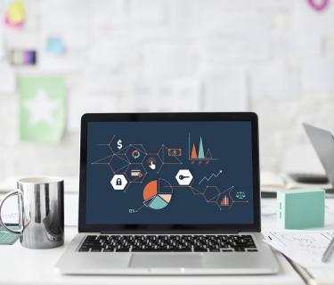 Laptop on desk with graphs on the screen