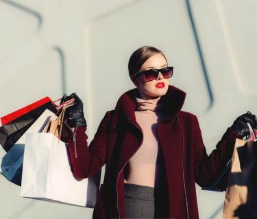 Woman wearing sunglasses and holding up multiple shopping bags