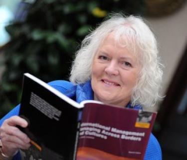 Woman smiling and reading text book outside