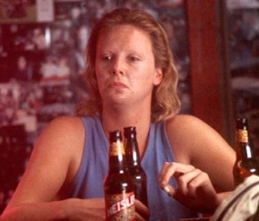 Woman sitting in a bar with 3 bottles of beer in front of her