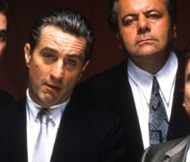 4 men in suits against a red background