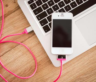 Iphone plugged into a laptop and resting on the laptop
