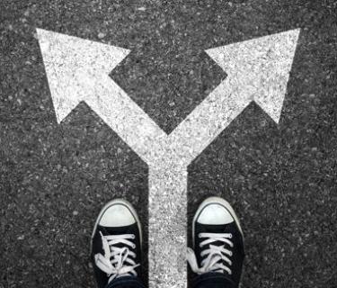 A pair of shoes on top of an arrow split and pointing in two directions