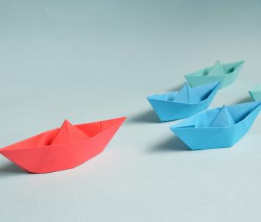 Five different coloured origami boats