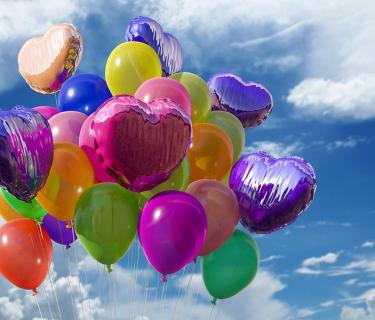 multiple different coloured balloons against a lightly cloudy sky