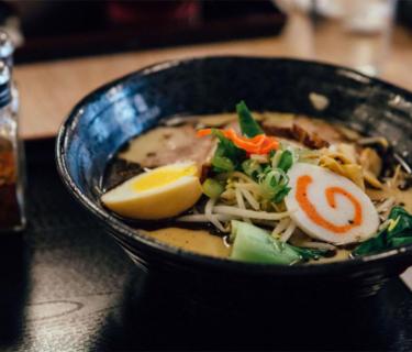 Noodle soup on a table with salt and pepper beside it