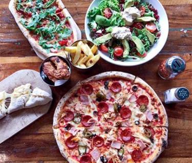 A restaurant table with pizza and salad on it