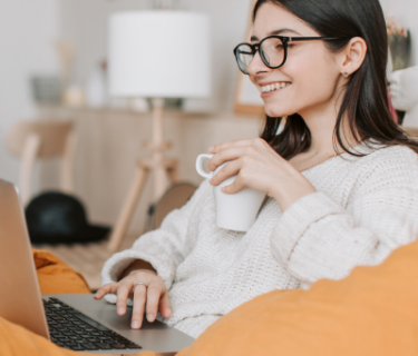 Woman drinking coffee and smiling with a laptop