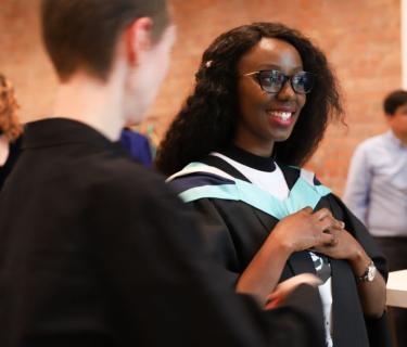 a student gets their gown ready for the ceremony