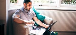 Arden University student on laptop at home by window