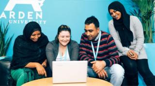 Blended students sitting around laptop