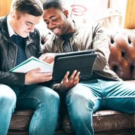 Two people looking at notepad and holding ipad
