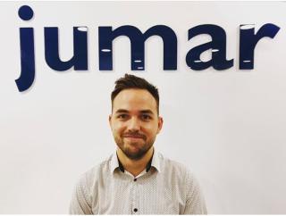 Head shot of man smiling with blue Jumar logo above head